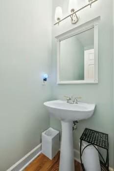 bathroom featuring baseboards, wood finished floors, and a sink