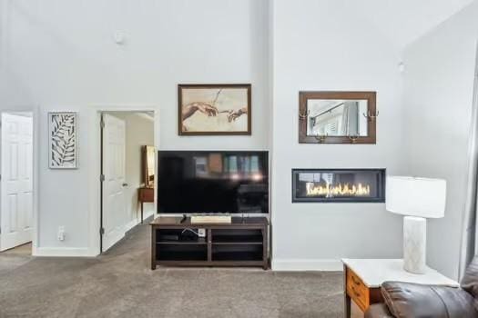 carpeted living room with baseboards and a glass covered fireplace