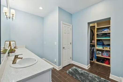 bathroom with wood finish floors, baseboards, double vanity, and a chandelier