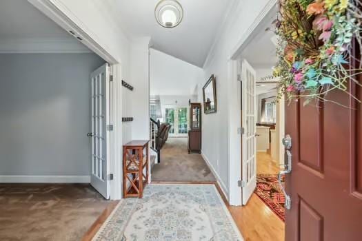 carpeted entrance foyer featuring baseboards, french doors, and vaulted ceiling