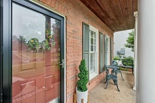 view of exterior entry featuring a porch and brick siding