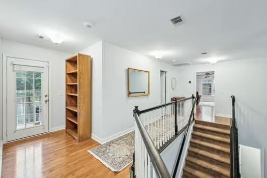hallway with an upstairs landing, light wood-type flooring, and baseboards