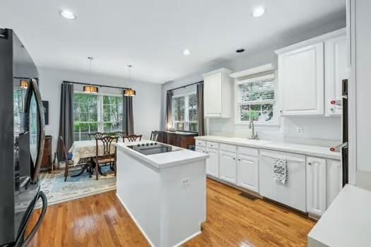kitchen featuring black appliances, a center island, white cabinets, light countertops, and recessed lighting