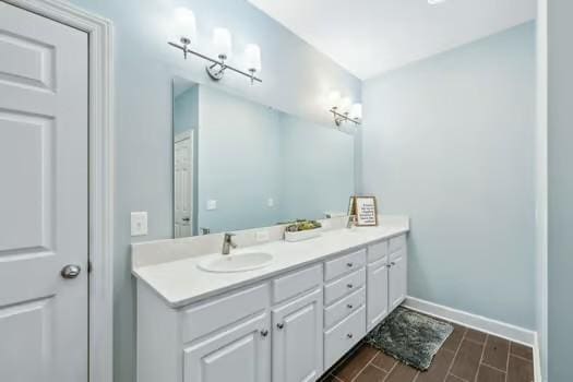 full bathroom featuring double vanity, baseboards, and wood finished floors