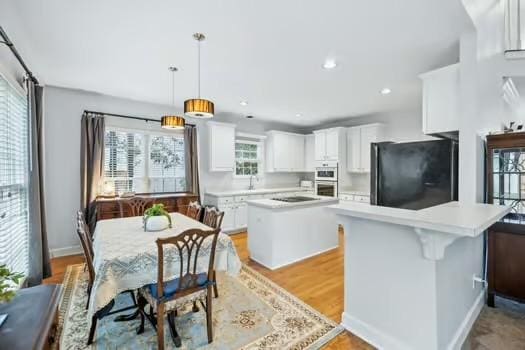 kitchen featuring black appliances, a center island, light countertops, white cabinets, and pendant lighting