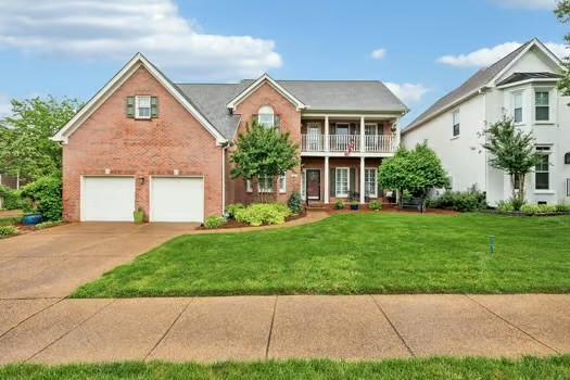 view of front of home featuring a garage, concrete driveway, a balcony, and a front yard