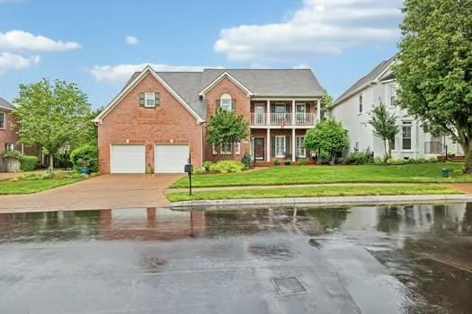 view of front of property featuring a front yard, a garage, driveway, and a water view