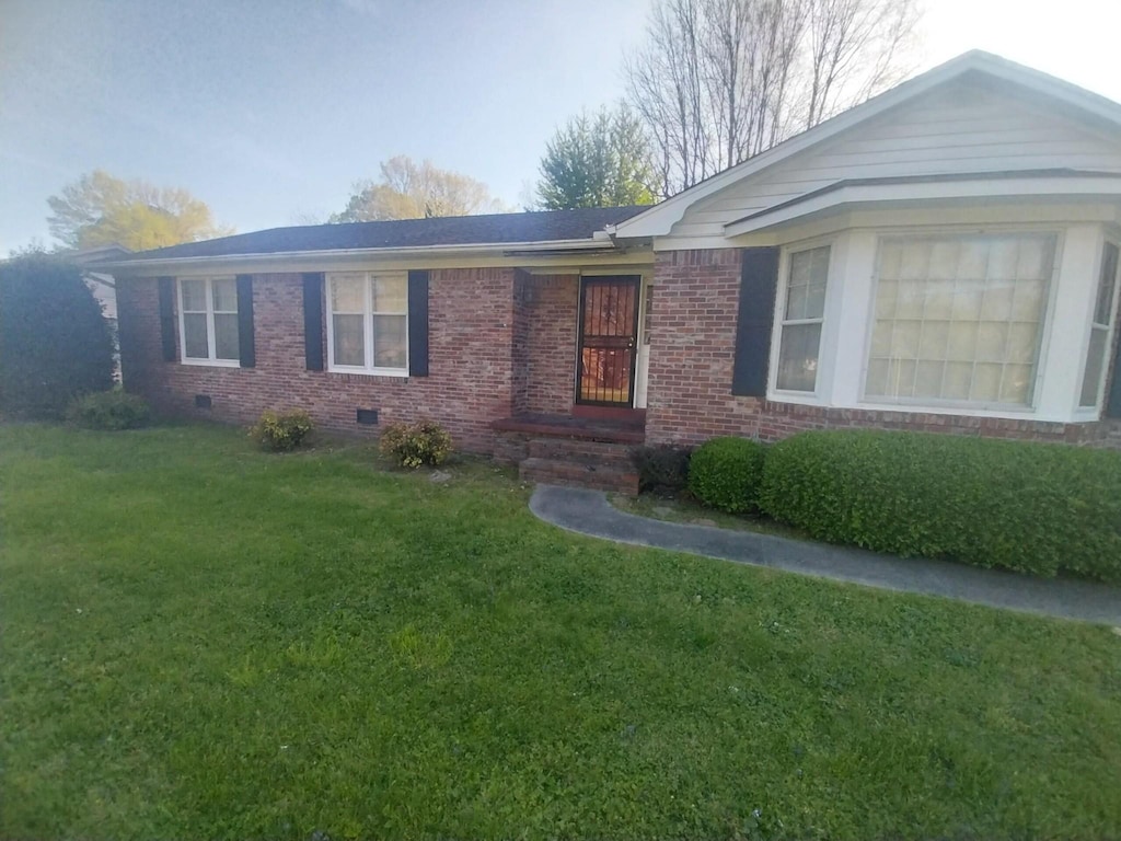 ranch-style home featuring brick siding, crawl space, and a front lawn