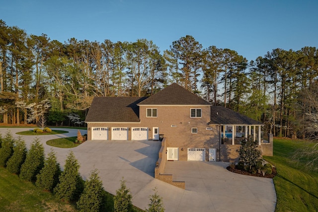 rear view of house featuring stucco siding, a lawn, a shingled roof, and concrete driveway