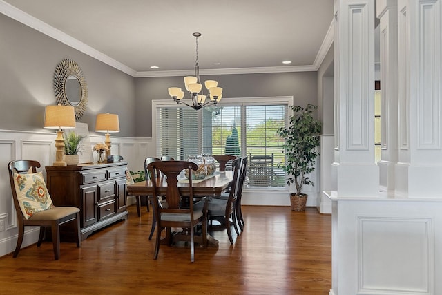 dining space featuring a decorative wall, crown molding, wainscoting, a chandelier, and dark wood-style flooring