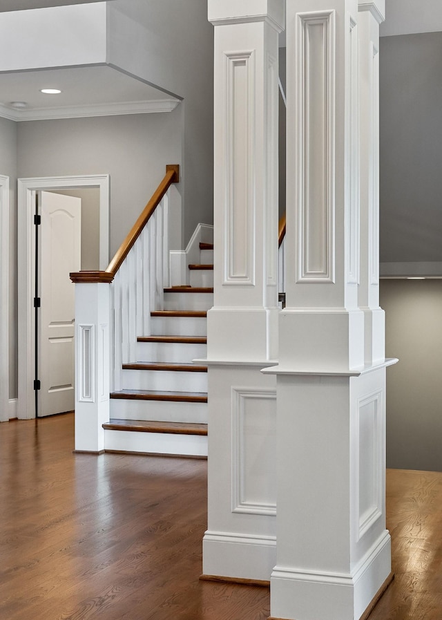 staircase featuring decorative columns, wood finished floors, and recessed lighting
