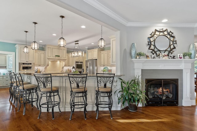 kitchen with stainless steel appliances, decorative backsplash, dark wood-type flooring, a breakfast bar area, and cream cabinets