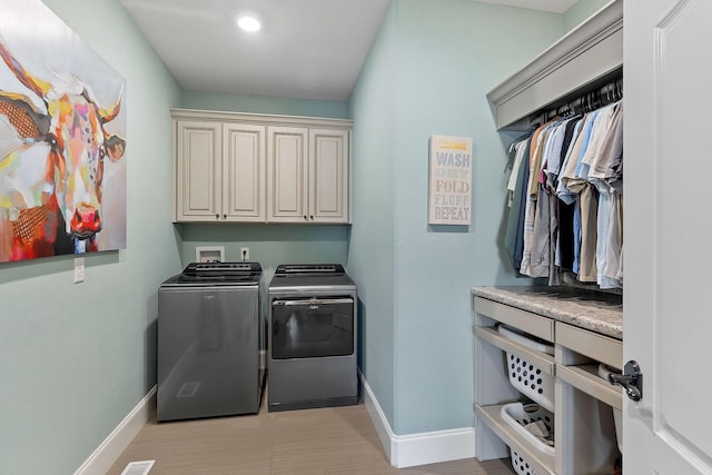 washroom featuring baseboards, washer and dryer, recessed lighting, and cabinet space