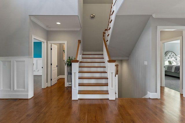 stairway featuring recessed lighting, wood finished floors, and crown molding