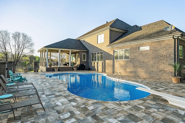 pool with a diving board, fence, a patio, and ceiling fan