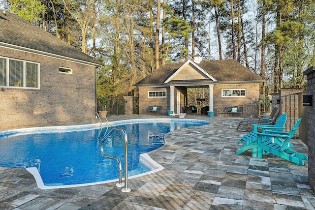 view of swimming pool with a fenced in pool, fence, a patio area, an outbuilding, and an exterior structure