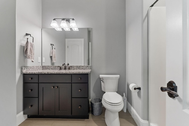 bathroom featuring vanity, toilet, and baseboards