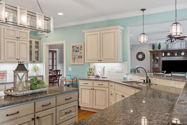 kitchen featuring cream cabinets, a ceiling fan, tasteful backsplash, and a sink