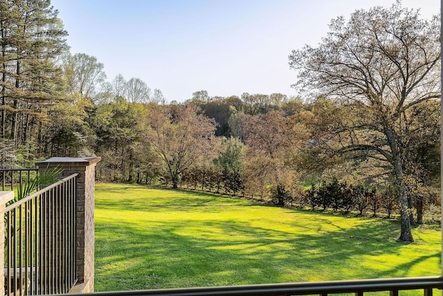 view of yard featuring a wooded view and fence