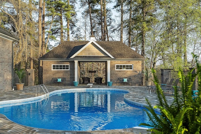 view of swimming pool with fence, a storage structure, a fenced in pool, and an outbuilding