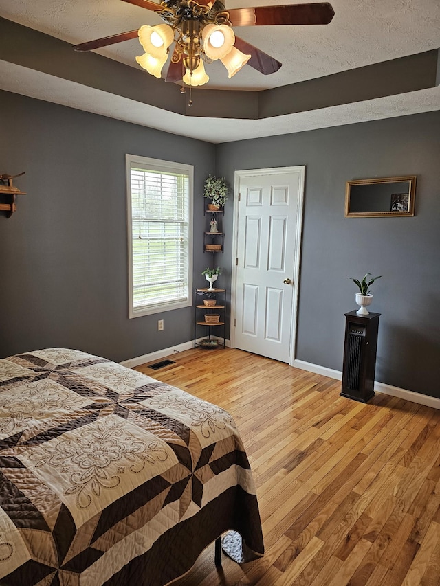 bedroom featuring light wood-style flooring, visible vents, a ceiling fan, and baseboards