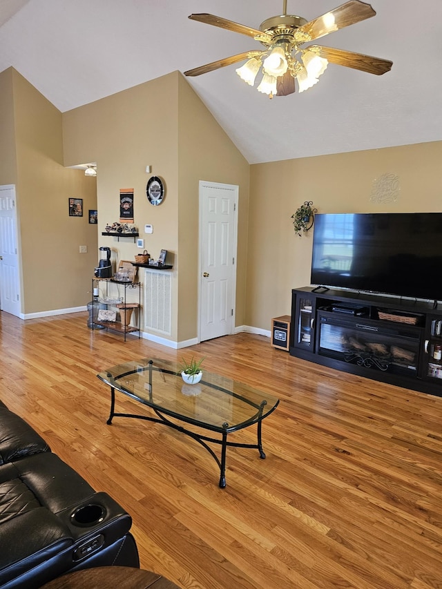 living area with high vaulted ceiling, wood finished floors, baseboards, and ceiling fan