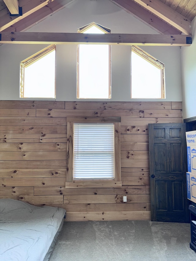 foyer entrance featuring lofted ceiling with beams, wood walls, and carpet floors