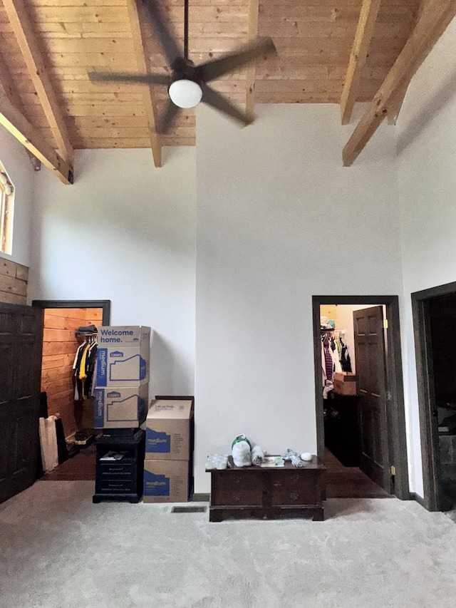 interior space featuring carpet flooring, beamed ceiling, ceiling fan, wood ceiling, and high vaulted ceiling