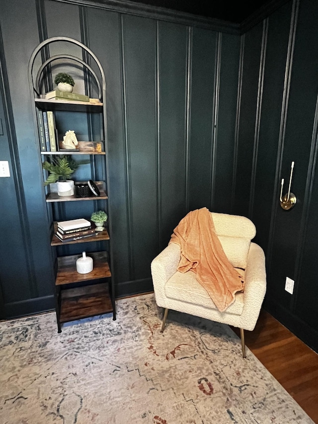 sitting room featuring wood finished floors and a decorative wall