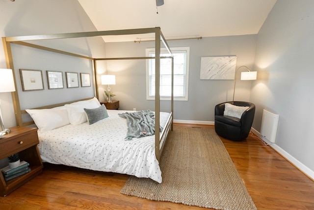 bedroom featuring baseboards, wood finished floors, and vaulted ceiling