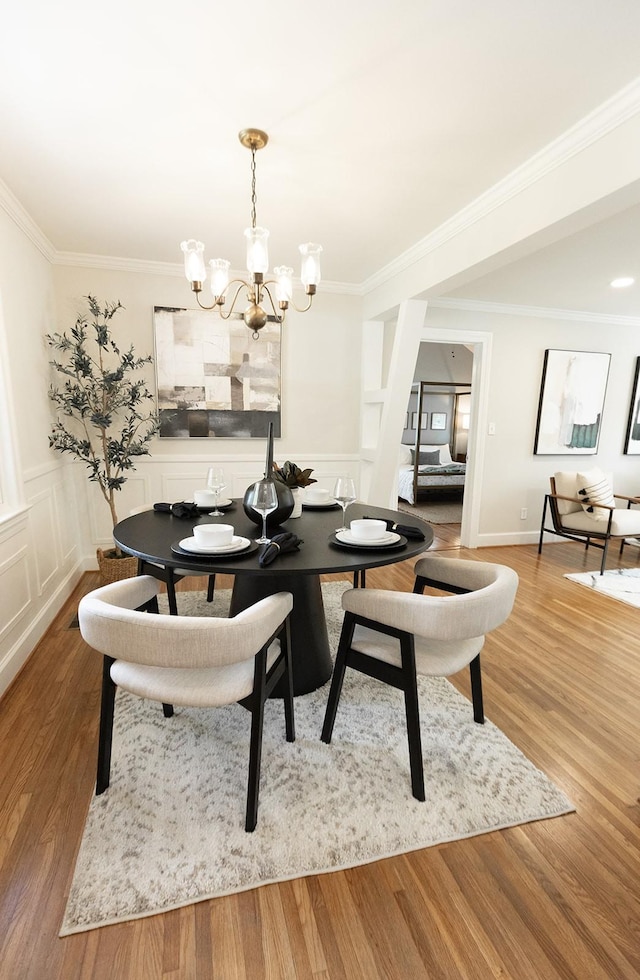 dining space with ornamental molding, wood finished floors, and a chandelier