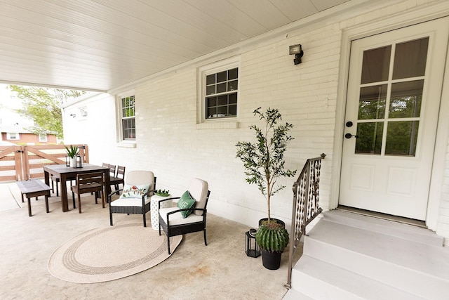 property entrance featuring brick siding, a patio, and outdoor dining space
