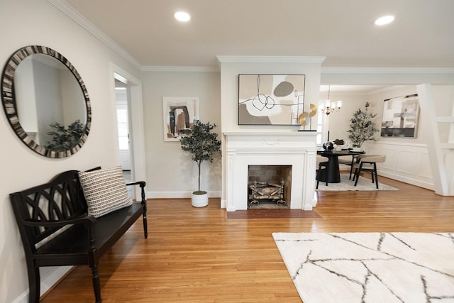 living area with a fireplace, recessed lighting, ornamental molding, and light wood-type flooring