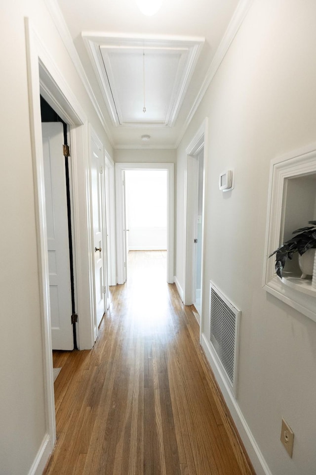 hallway with visible vents, wood finished floors, and attic access