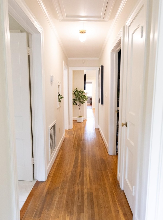 hall featuring baseboards, visible vents, wood finished floors, and attic access