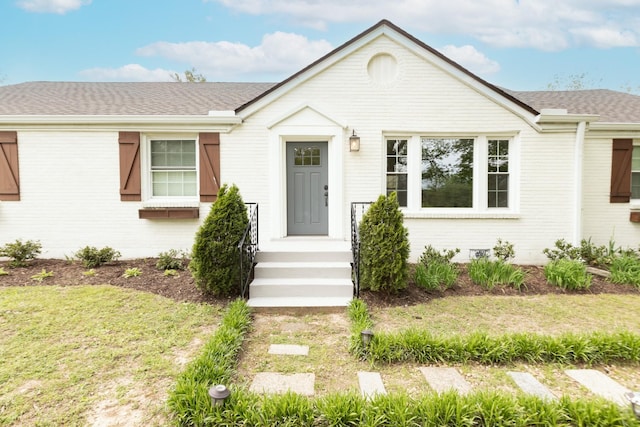 ranch-style house featuring brick siding, a shingled roof, and a front lawn