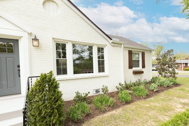 view of side of home featuring roof with shingles and brick siding