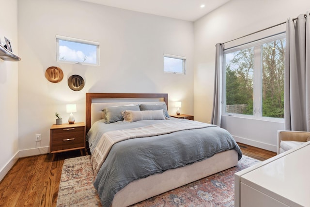 bedroom featuring baseboards, multiple windows, and wood finished floors