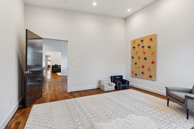 sitting room featuring baseboards, wood finished floors, recessed lighting, and a high ceiling