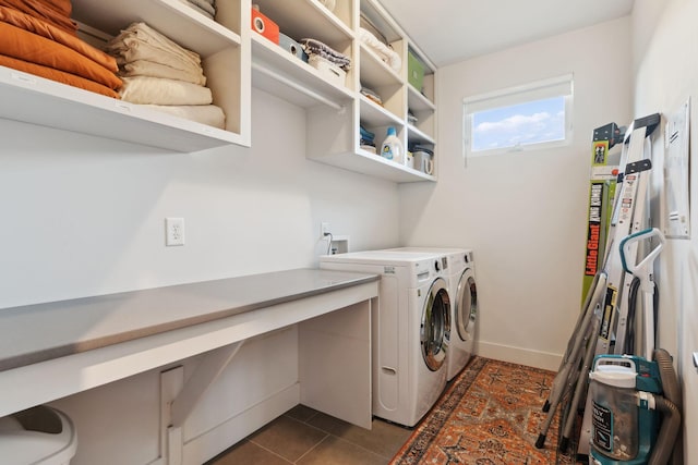 clothes washing area with baseboards, dark tile patterned floors, washer and clothes dryer, and laundry area