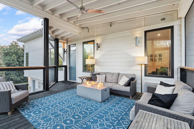 sunroom / solarium featuring ceiling fan, beam ceiling, and an outdoor living space with a fire pit
