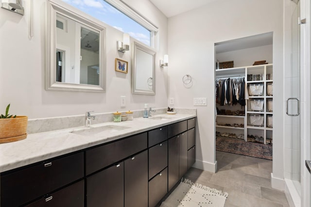 full bath featuring double vanity, a sink, a shower stall, and a walk in closet