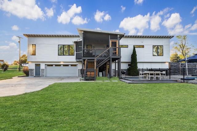 view of front of house featuring stairway, concrete driveway, a garage, a wooden deck, and a sunroom