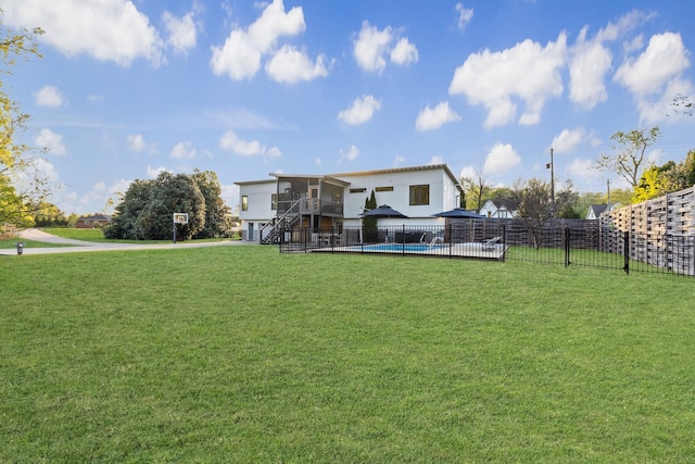 view of yard featuring fence, a fenced in pool, and stairway
