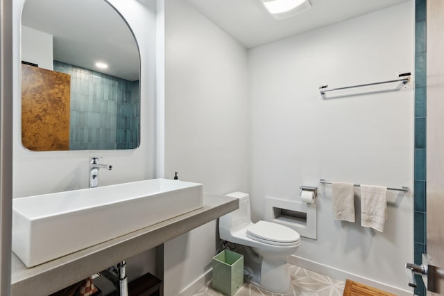 full bathroom featuring toilet, baseboards, and a sink