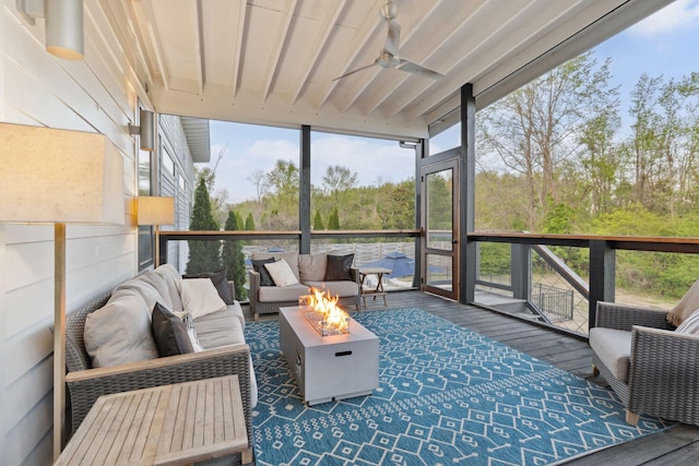 sunroom featuring a ceiling fan and an outdoor living space with a fire pit