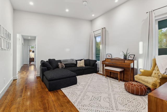 living area with dark wood-type flooring, a high ceiling, baseboards, and recessed lighting