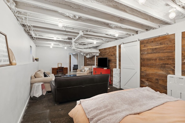 finished below grade area featuring wood walls, baseboards, and a barn door