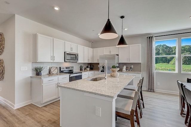 kitchen featuring baseboards, appliances with stainless steel finishes, a sink, and light wood-style flooring