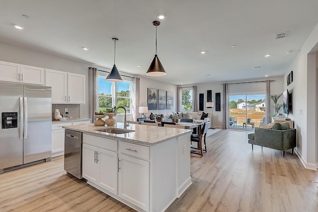 kitchen featuring light wood finished floors, a sink, open floor plan, visible vents, and appliances with stainless steel finishes
